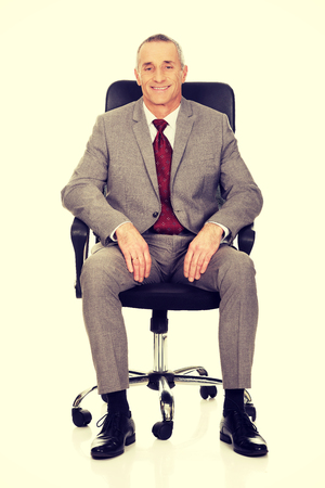 Smiling mature businessman sitting on armchair.の写真素材