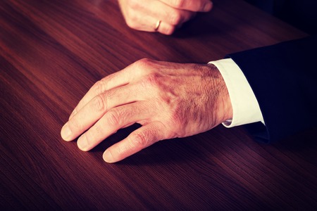 Mature businessman's hands put on the desk.の写真素材
