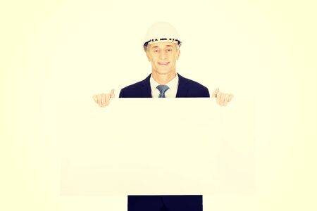 Mature engineer with hard hat holding empty banner.の写真素材