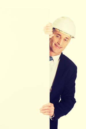 Mature engineer with hard hat holding empty banner.の写真素材