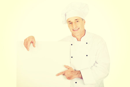 Experienced chef in white uniform holding empty banner.の写真素材