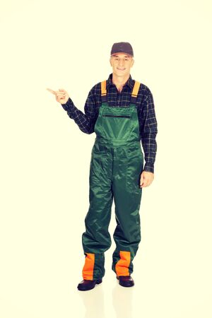 Experienced smiling gardener in uniform pointing to the leftの写真素材
