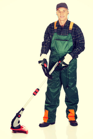 Experienced gardener trimming with ear protectors