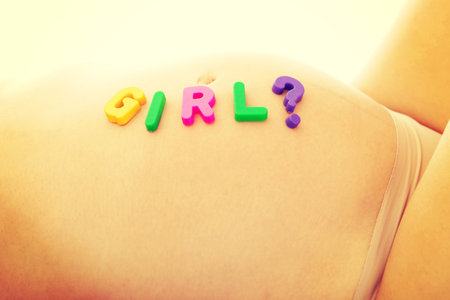 Belly of pregnant woman with girl lettering questionの写真素材