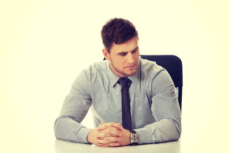 Thoughtful businessman sitting by a desk in the office.の写真素材