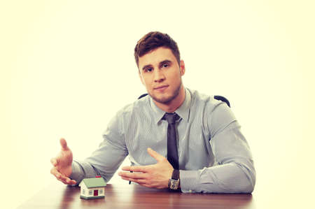 Handsome talking businessman with house model by a desk.の写真素材