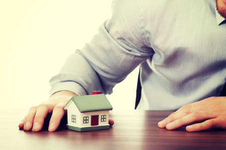 Happy businessman with house model by a desk.の写真素材