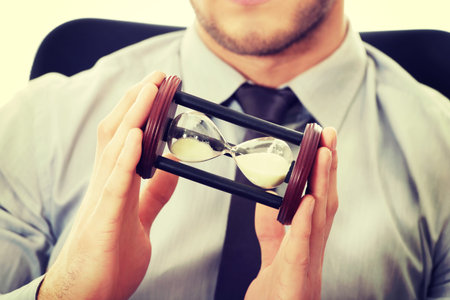 Businessman holding hourglass in the office.
