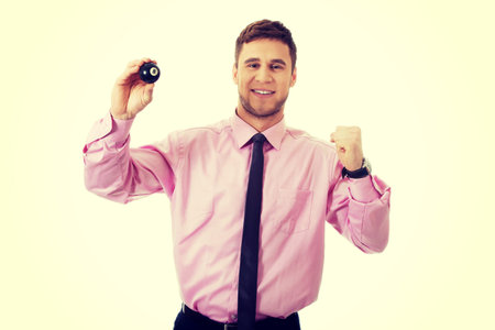 Young handsome businessman holding billiard ball.