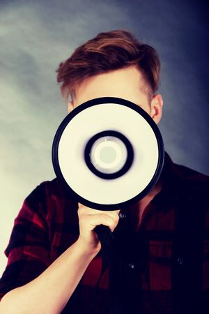 Young handsome man shouting in megaphone.の写真素材
