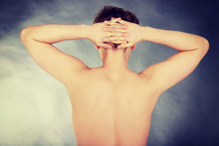 Young shirtless man with hands on head.の写真素材