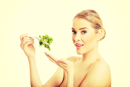 Happy nude woman eating lettuceの写真素材