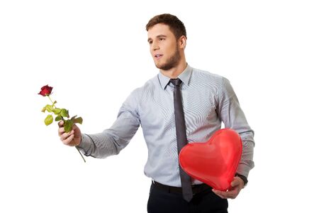 Young happy man with red rose and heart balloon.の写真素材