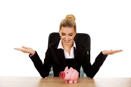 Businesswoman with a piggybank behind the desk.の写真素材