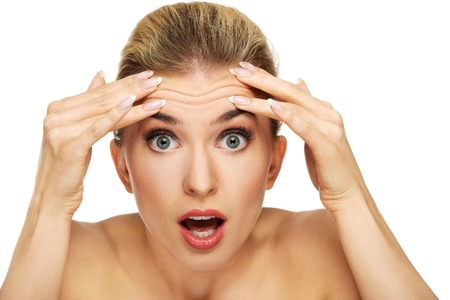 A young woman checking wrinkles on her forehead, closeupの写真素材
