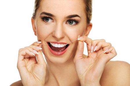 Young caucasian woman flossing her teeth, isolated on white