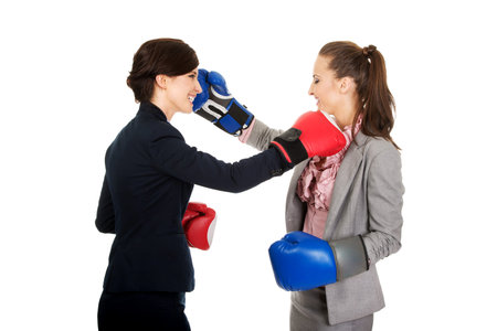 Two beautiful business women with boxing gloves fighting.