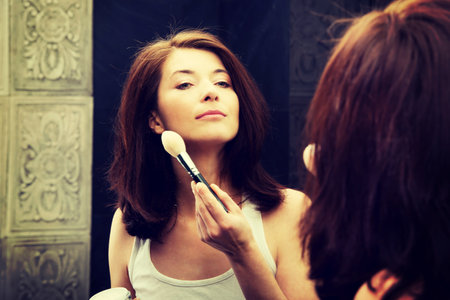 Beautiful woman doing make up in bathroom.の写真素材
