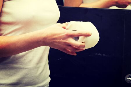 Woman holding toilet paper in bathroom.の写真素材