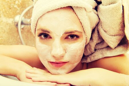 Young spa woman relaxing in bathroom with cream moisturizer.の写真素材
