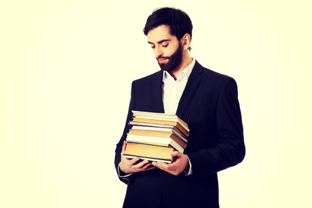 Young happy businessman holding stack of books.の写真素材