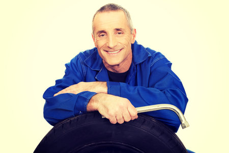 Mature car mechanic with a tire and wrench.の写真素材