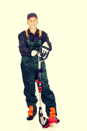 Experienced gardener with trimmer and ear protectors