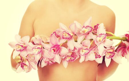 Beautiful woman covering breast with flower.の写真素材