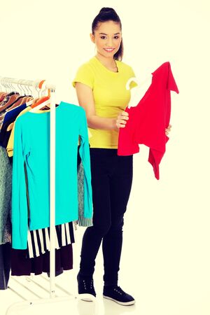 Beautiful young woman with a shirt thinking what to dress.の写真素材