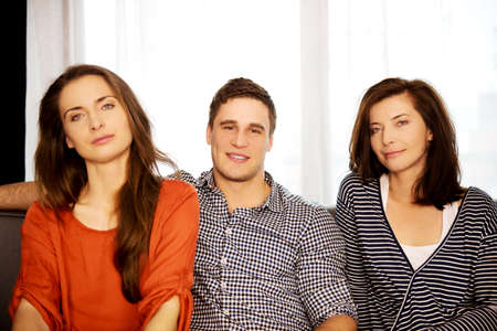 Sisters and brother sitting on the sofa.の写真素材