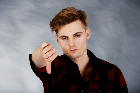 Young upset man showing thumbs down.の写真素材