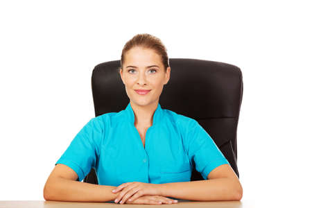 Young female doctor or nurse sitting behind the desk.の写真素材