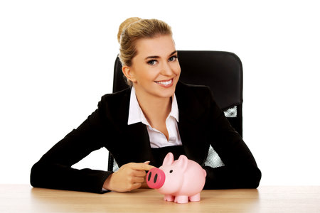 Businesswoman with a piggybank behind the desk.の写真素材