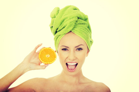 Beautiful happy woman holding an orange.の写真素材