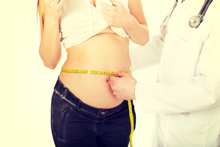 Doctor measuring her pregnant patient growing bellyの写真素材