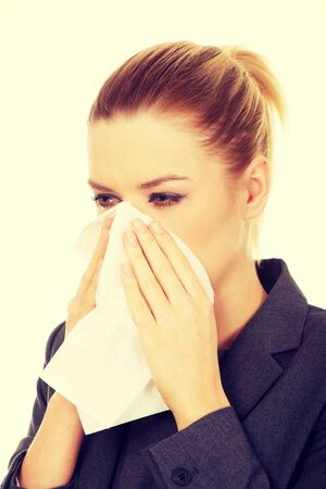 Businesswoman with an allergy sneezing into tissue.の写真素材