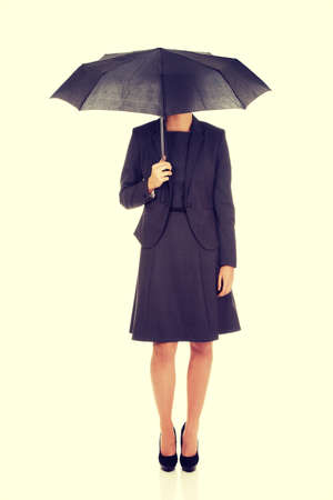 Businesswoman covering her head with umbrella.の写真素材