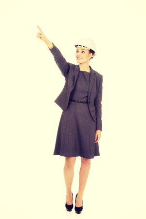 Happy businesswoman in hard hat pointing up.の写真素材