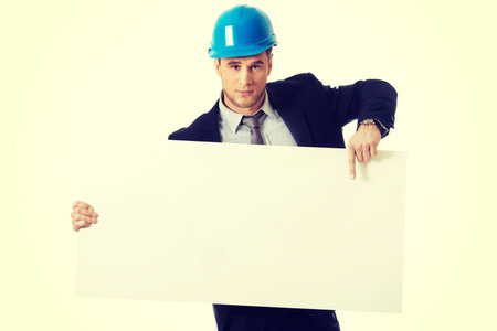 Handsome businessman in hard hat holding empty banner.