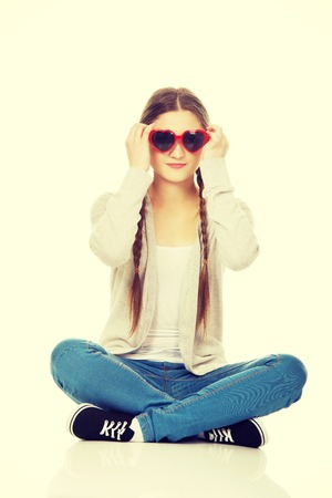Funny teen woman sitting wearing sunglasses.の写真素材