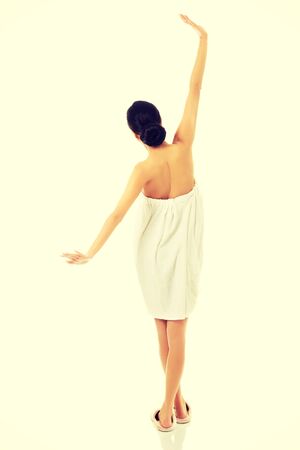 Spa woman wrapped in towel stretching her armsの写真素材