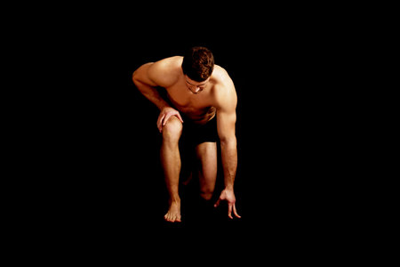 Artistic muscular man bending down.