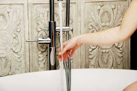 Beautiful woman pours water in a bath.の写真素材