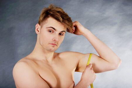 Young fitness man measuring his biceps.の写真素材