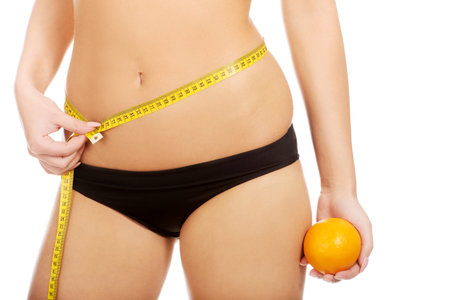 Slim woman with apple measuring her waist.の写真素材