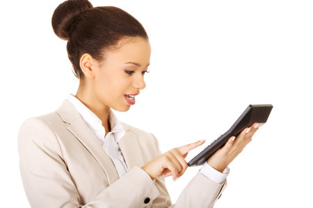 Smiling african business woman counting on calculator.の写真素材