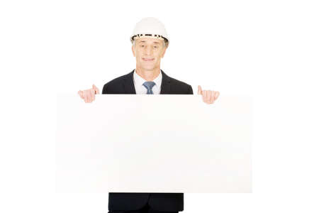 Mature engineer with hard hat holding empty banner.の写真素材