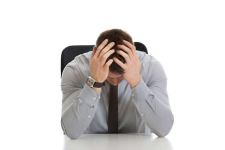 Worried businessman sitting by a desk in the office.の写真素材
