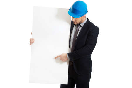 Handsome businessman in hard hat pointing on empty banner.の写真素材