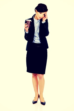 Exhausted businesswoman holding a cup of coffee.の写真素材